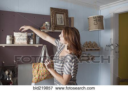 Stock Photo - Caucasian business owner arranging items in store. Fotosearch