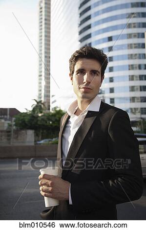 Stock Photograph - Caucasian businessman drinking coffee outdoors. Fotosearch