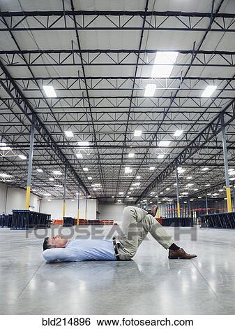 Caucasian businessman laying on floor in empty warehouse View Large Photo Image Stock Photograph - Caucasian businessman laying on floor in empty warehouse. Fotosearch