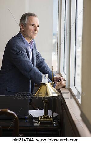 Caucasian businessman looking out office window View Large Photo Image Picture - Caucasian businessman looking out office window. Fotosearch