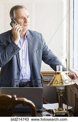 Caucasian businessman looking out office window View Large Photo Image Stock Image - Caucasian businessman looking out office window. Fotosearch