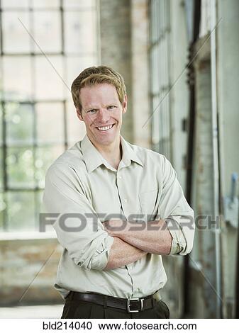 Stock Image - Caucasian businessman smiling in warehouse. Fotosearch