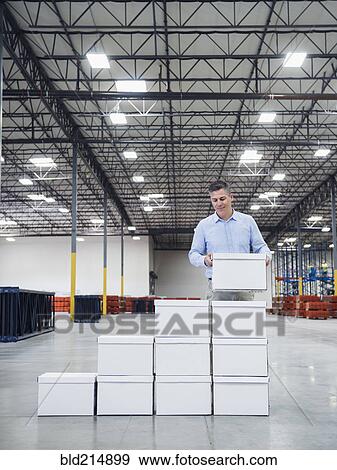 Caucasian businessman stacking boxes in warehouse View Large Photo Image Stock Photo - Caucasian businessman stacking boxes in warehouse. Fotosearch