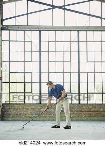 Caucasian businessman sweeping warehouse floor View Large Photo Image Picture - Caucasian businessman sweeping warehouse floor. Fotosearch