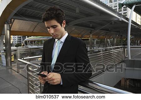 Caucasian businessman text messaging on cell phone outdoors View Large Photo Image Stock Photo - Caucasian businessman text messaging on cell phone outdoors. Fotosearch
