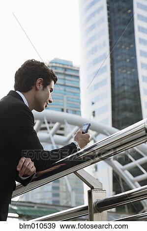 Caucasian businessman text messaging on cell phone outdoors View Large Photo Image Stock Photo - Caucasian businessman text messaging on cell phone outdoors. Fotosearch