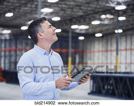 Caucasian businessman using digital tablet in empty warehouse View Large Photo Image Stock Image - Caucasian businessman using digital tablet in empty warehouse. Fotosearch