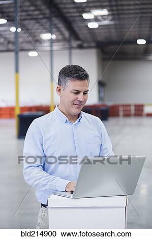 Caucasian businessman using laptop in empty warehouse View Large Photo Image Stock Image - Caucasian businessman using laptop in empty warehouse. Fotosearch