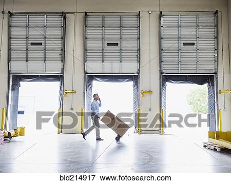 Caucasian businessman wheeling cardboard boxes in warehouse View Large Photo Image Stock Photo - Caucasian businessman wheeling cardboard boxes in warehouse. Fotosearch