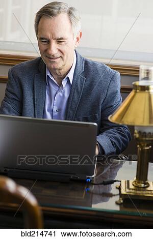 Caucasian businessman working on laptop at desk View Large Photo Image Stock Image - Caucasian businessman working on laptop at desk. Fotosearch