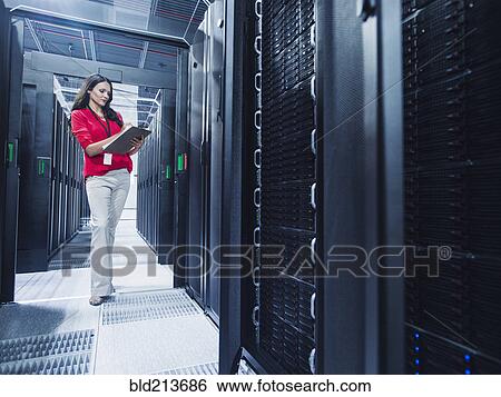 Stock Photograph - Caucasian businesswoman reading clipboard in server room. Fotosearch