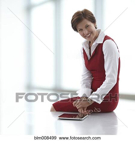Caucasian businesswoman sitting on table with digital tablet View Large Photo Image Stock Photo - Caucasian businesswoman sitting on table with digital tablet. Fotosearch