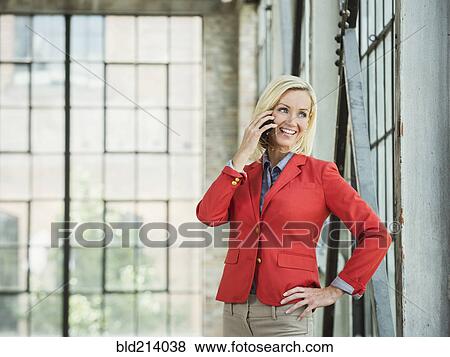 Stock Photo - Caucasian businesswoman talking on cell phone in warehouse. Fotosearch