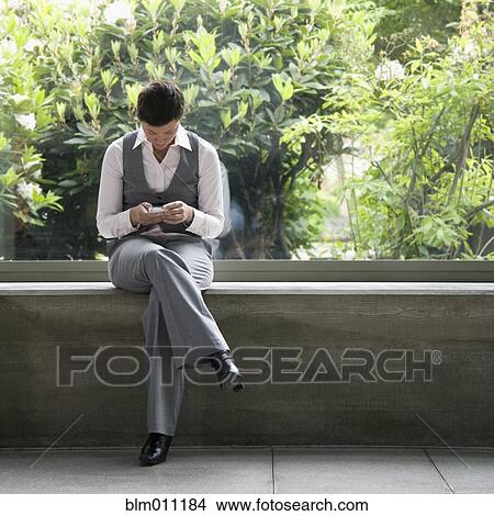 Picture - Caucasian businesswoman text messaging outdoors. Fotosearch