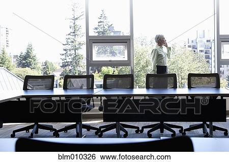 Stock Photograph - Caucasian businesswoman using cell phone in conference room. Fotosearch