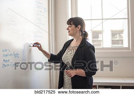 Stock Photography - Caucasian businesswoman writing on whiteboard in office. Fotosearch