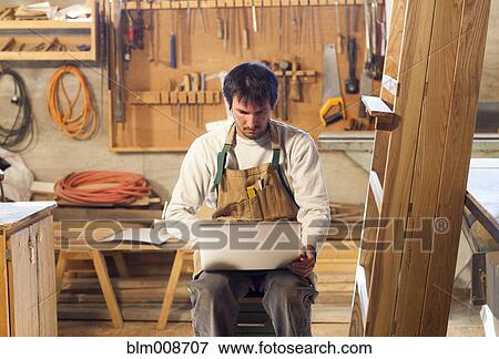 Caucasian carpenter using laptop in workshop View Large Photo Image Stock Photo - Caucasian carpenter using laptop in workshop. Fotosearch