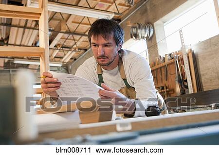 Stock Image - Caucasian carpenter working in workshop. Fotosearch