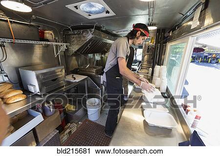 Stock Image - Caucasian chef working in food truck kitchen. Fotosearch