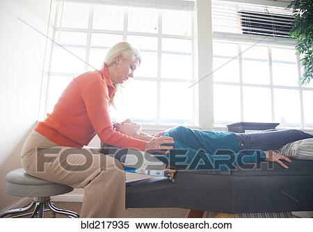 Stock Photography - Caucasian chiropractor massaging shoulders of client. Fotosearch