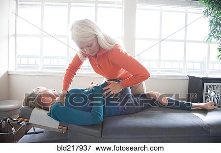 Stock Photo - Caucasian chiropractor stretching back of client. Fotosearch
