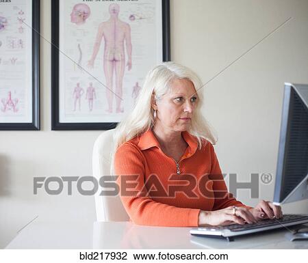 Stock Image - Caucasian chiropractor working at computer. Fotosearch