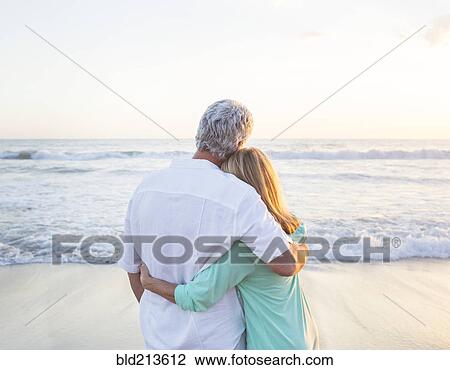 Stock Image - Caucasian couple hugging on beach. Fotosearch