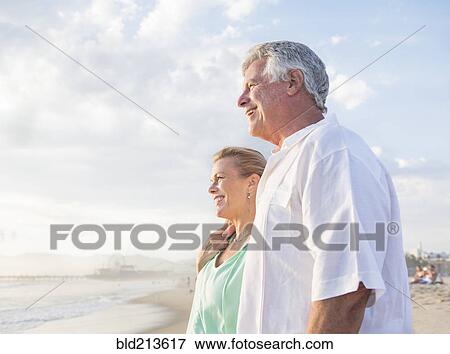 Stock Photo - Caucasian couple hugging on beach. Fotosearch