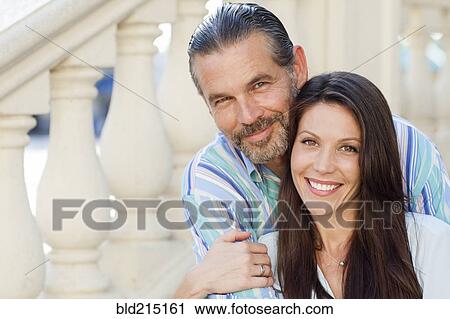 Stock Image - Caucasian couple hugging on front stoop. Fotosearch
