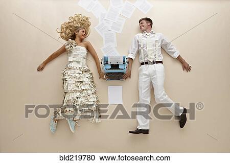 Stock Image - Caucasian couple laying near typewriter on floor. Fotosearch