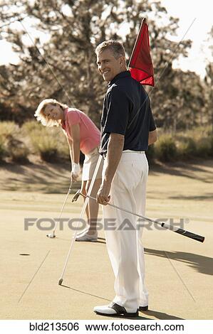 Stock Photograph - Caucasian couple playing golf on course. Fotosearch