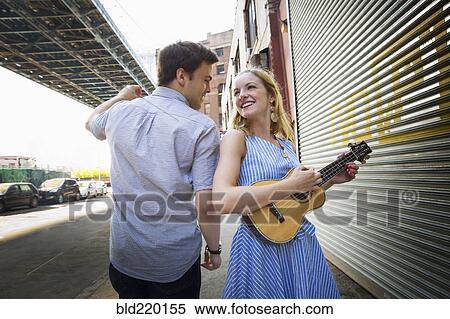 Stock Photography - Caucasian couple playing ukulele in city. Fotosearch