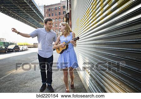 Picture - Caucasian couple playing ukulele on city sidewalk. Fotosearch