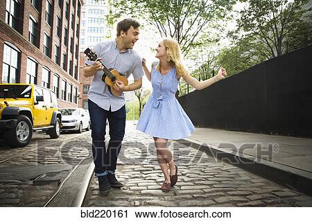 Caucasian couple playing ukulele on city street View Large Photo Image Stock Image - Caucasian couple playing ukulele on city street. Fotosearch
