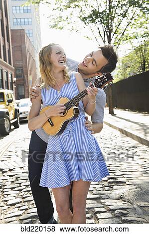 Stock Photo - Caucasian couple playing ukulele on city street. Fotosearch