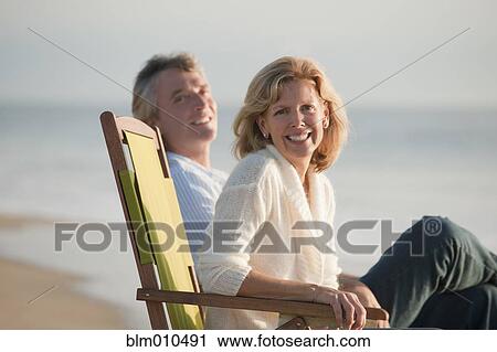 Caucasian couple sitting on folding chairs on beach View Large Photo Image Stock Image - Caucasian couple sitting on folding chairs on beach. Fotosearch
