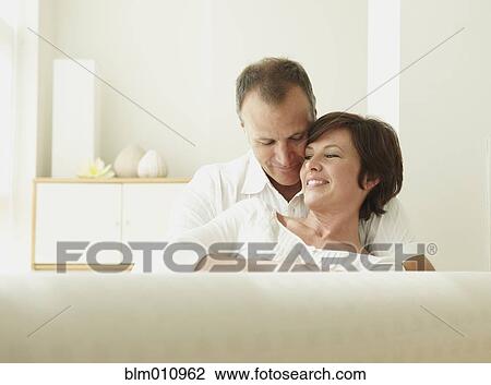 Caucasian couple sitting on sofa hugging View Large Photo Image Stock Image - Caucasian couple sitting on sofa hugging. Fotosearch