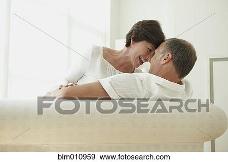 Stock Photo - Caucasian couple sitting on sofa laughing. Fotosearch