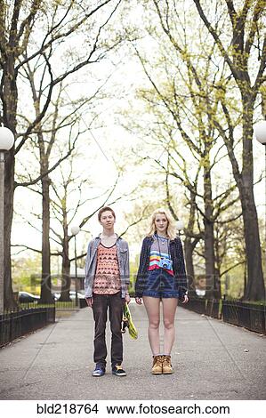 Picture - Caucasian couple standing in park with skateboard. Fotosearch