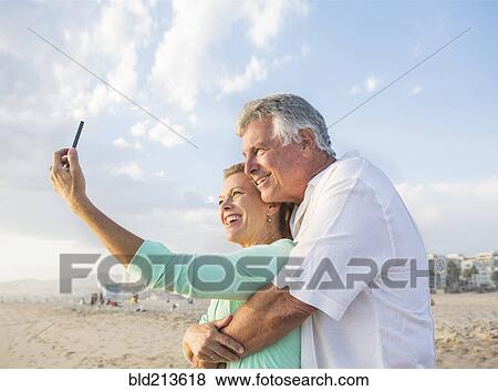 Caucasian couple taking cell phone selfie on beach View Large Photo Image Stock Photo - Caucasian couple taking cell phone selfie on beach. Fotosearch