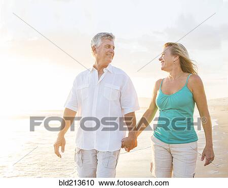 Stock Image - Caucasian couple walking on beach. Fotosearch