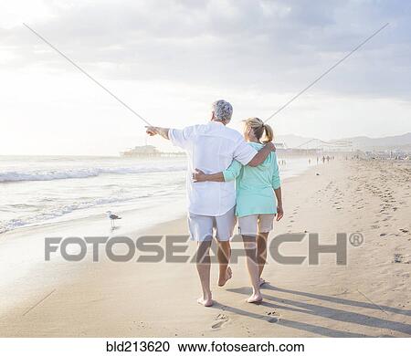 Stock Image - Caucasian couple walking on beach. Fotosearch