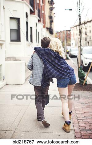 Stock Photo - Caucasian couple walking on city sidewalk. Fotosearch
