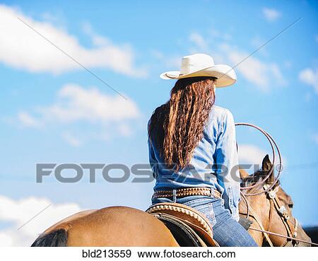 Stock Photo - Caucasian cowgirl riding horse in rodeo outdoors. Fotosearch