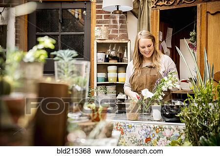 Stock Photo - Caucasian employee caring for plants in nursery. Fotosearch