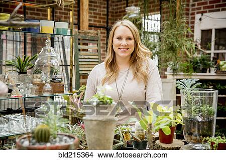 Picture - Caucasian employee smiling in plant nursery. Fotosearch