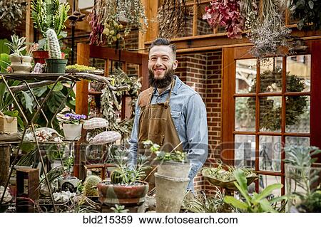 Caucasian employee smiling in plant nursery View Large Photo Image Stock Photo - Caucasian employee smiling in plant nursery. Fotosearch