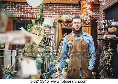 Stock Photography - Caucasian employee smiling in plant nursery. Fotosearch