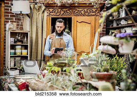 Caucasian employee using digital tablet in plant nursery View Large Photo Image Stock Photo - Caucasian employee using digital tablet in plant nursery. Fotosearch
