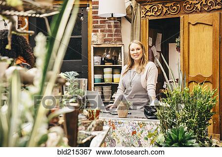 Stock Photo - Caucasian employee using laptop in plant nursery. Fotosearch
